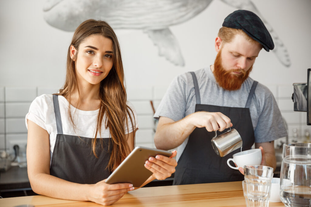 Website SODEW 5 coffee business concept cheerful baristas looking their tablets online orders modern coffee shop